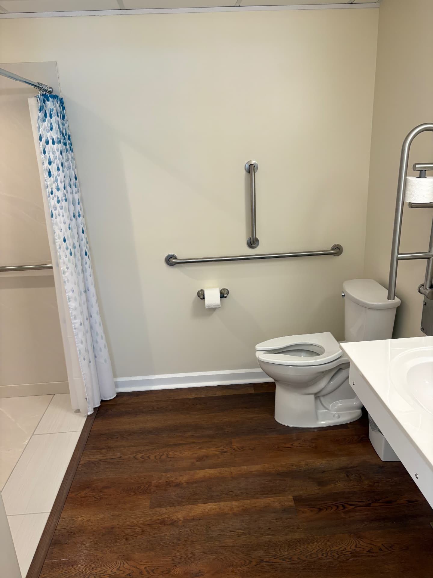 Clean commercial restroom with walk-in shower and grab bars